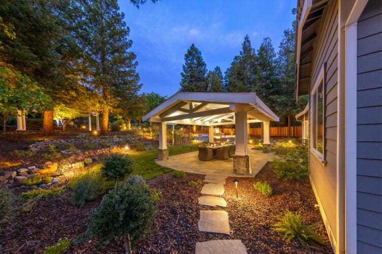 Stone garden path and planting leading to a covered outdoor seating area at dusk