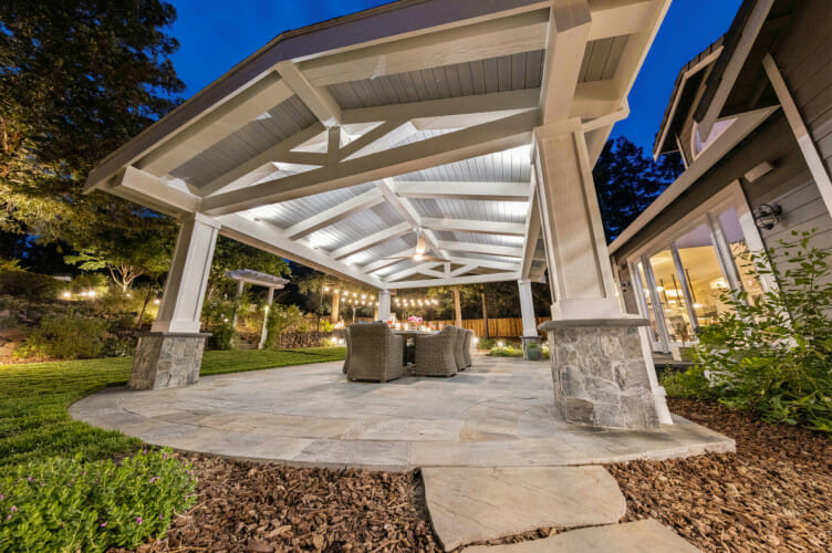 Solid patio cover with exposed beams above an outdoor seating and dining area